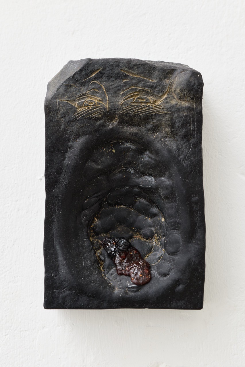 A black wall relief with an oval cavity and fine gold-colored lines.